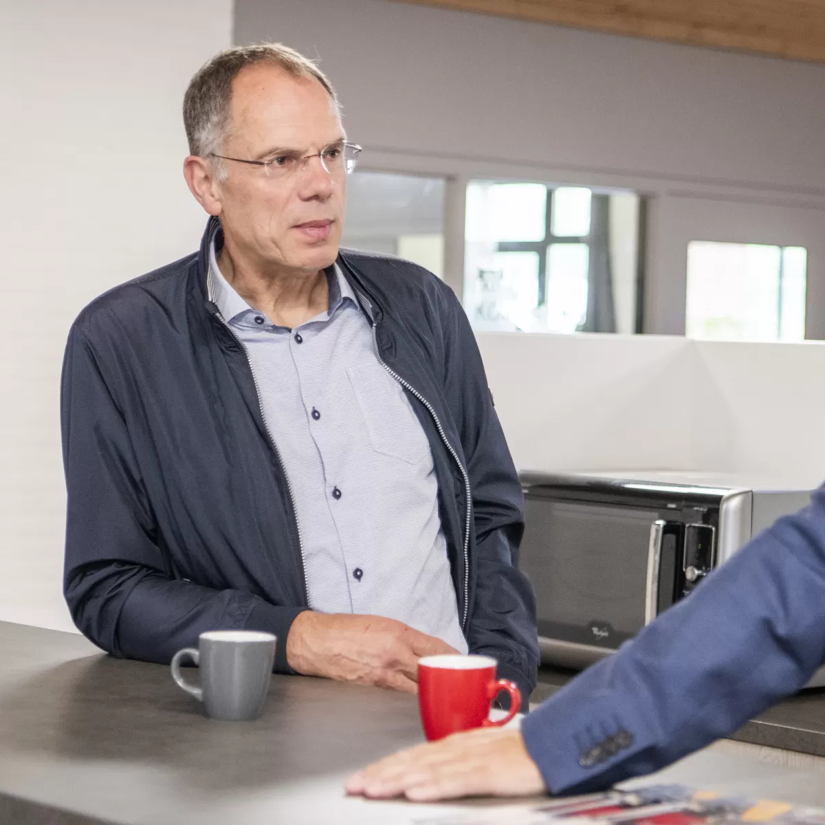 Overlegsituatie - twee mensen die overleggen aan een aanrecht met koffie